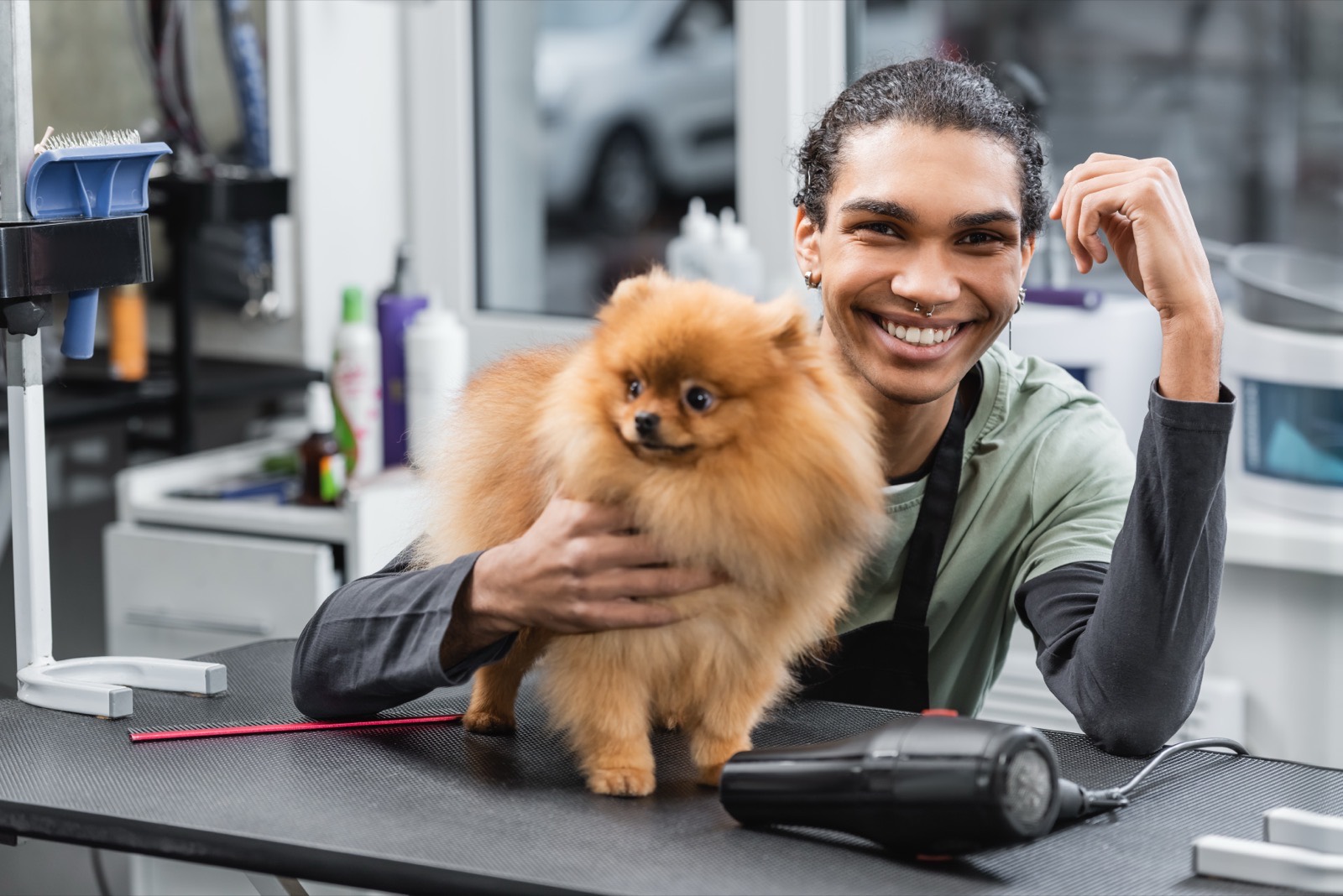 Casey, a Paws & Suds groomer, smiling with a small dog